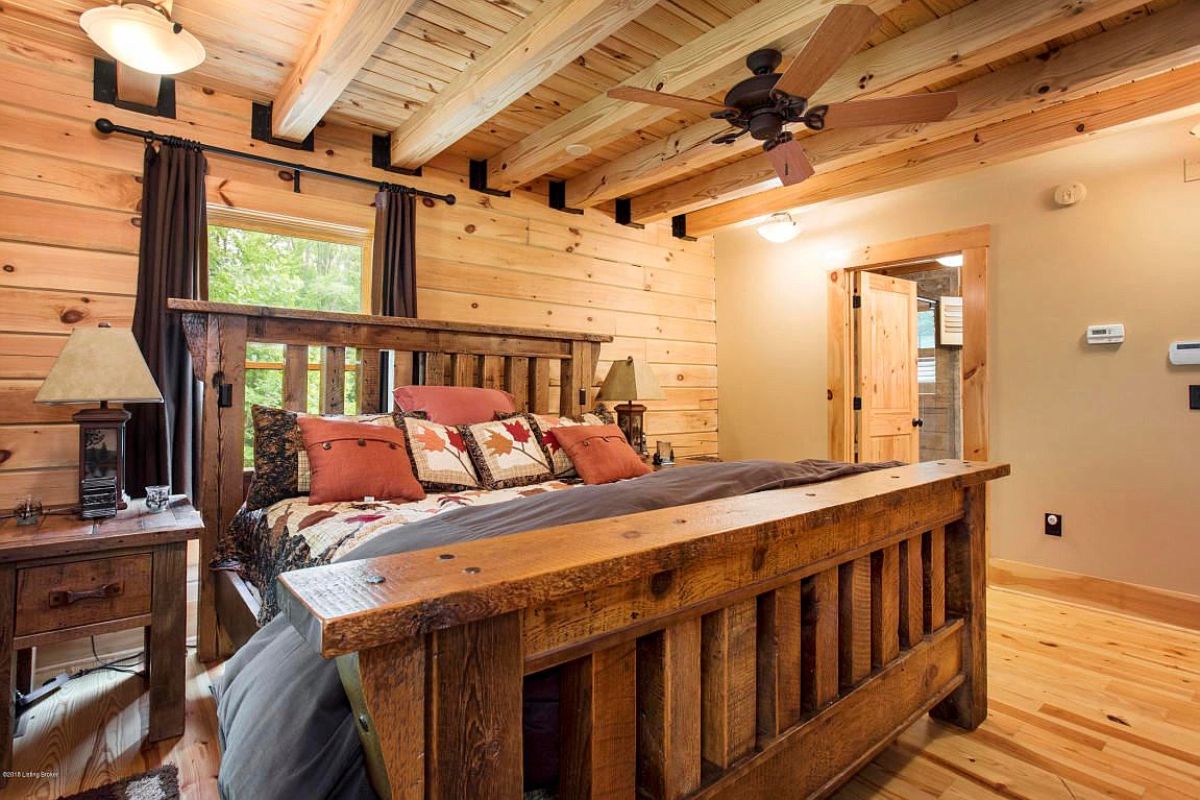 gray and red bedding on wood bed frame with ceiling fan above