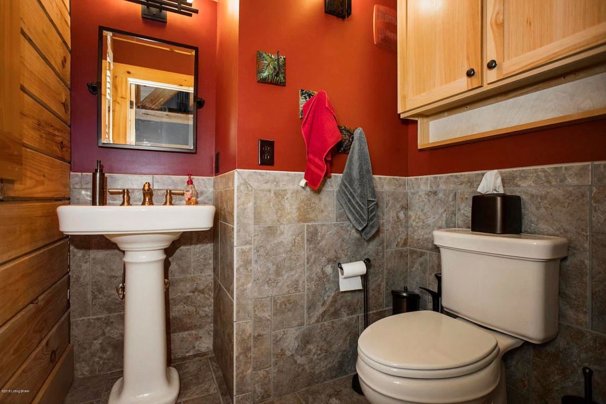 gray tile bottom wall with red wall above in bathroom with white pedastal sink