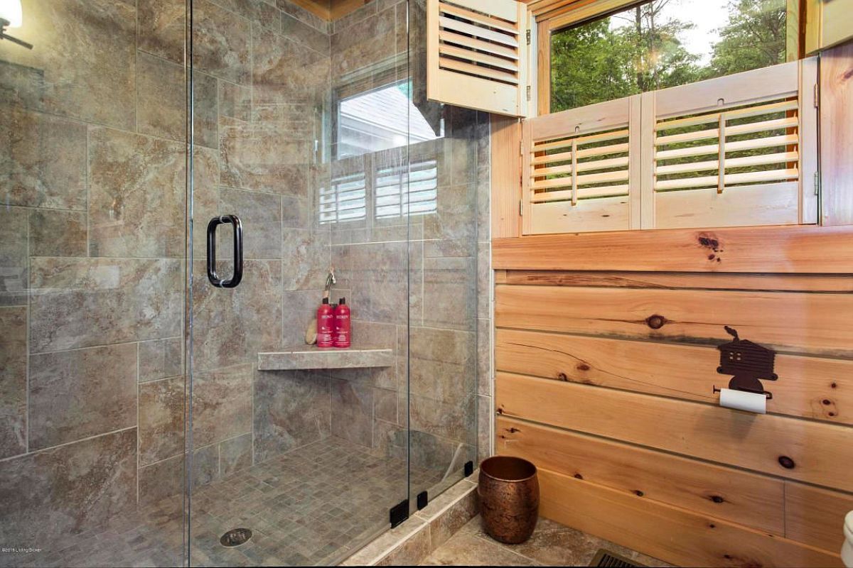 gray tile in shower with glass door in bathroom with wood walls