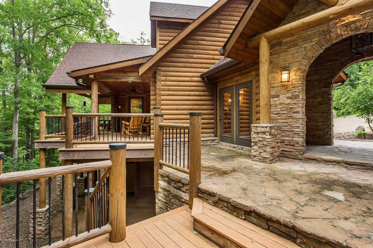 open deck on back of log cabin with rock patio and wood deck