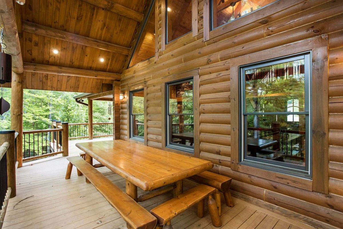 wood picnic table under awning of porch on back of cabin