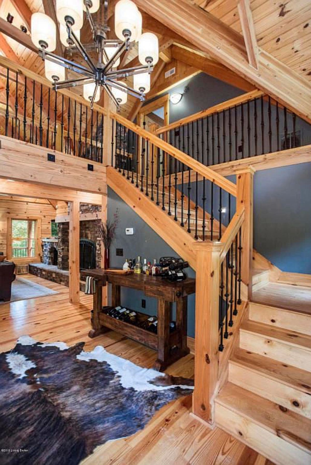 gray wall behind wood stairs to loft with wood and black iron spindle railing