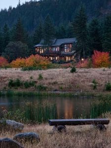 view across pond to log cabin on hill behind fall foliage