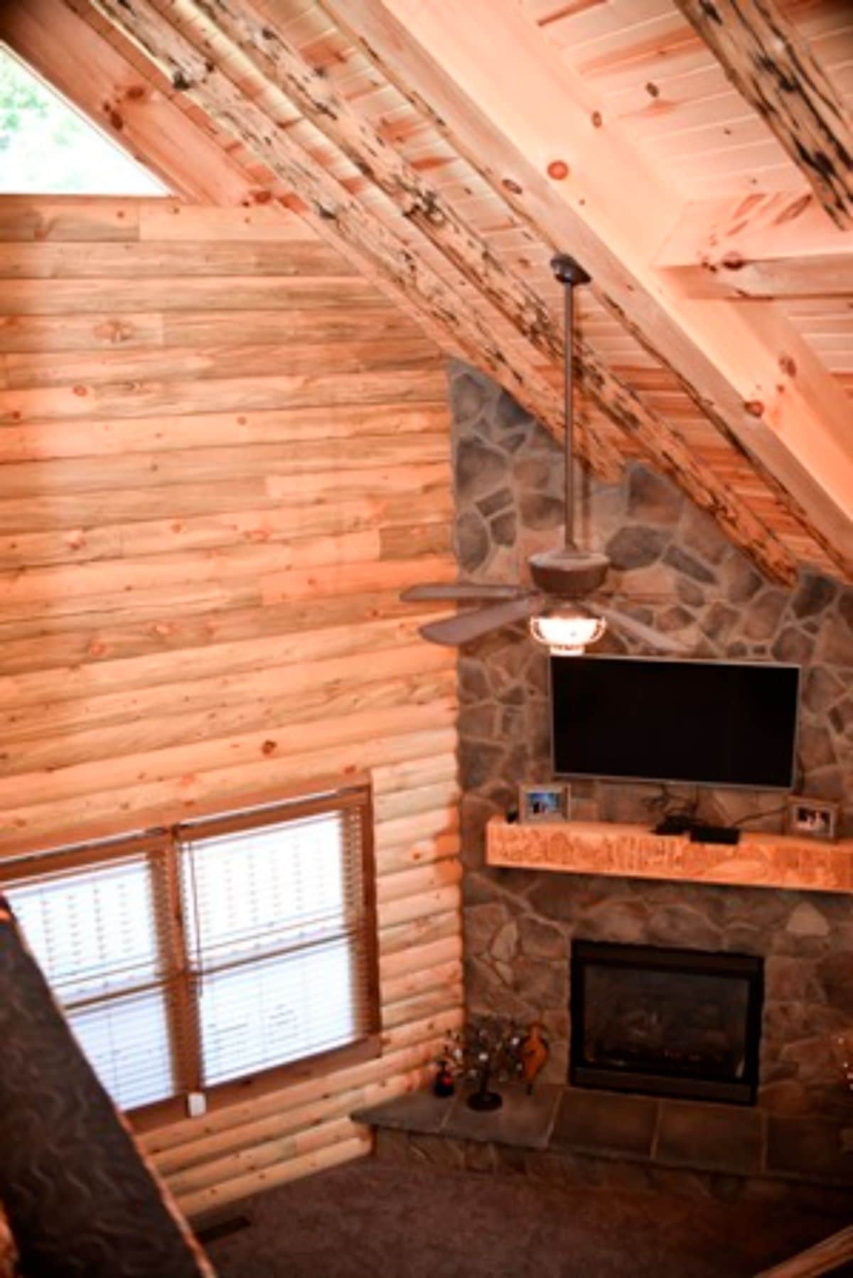 stone fireplace in corner of log cabin with log mantle