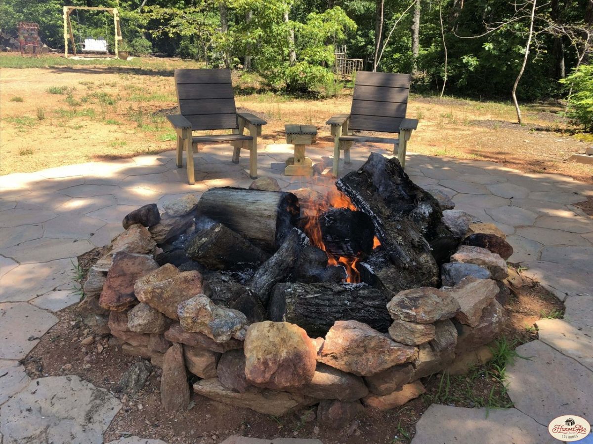 stone fire pit outside cabin with chairs