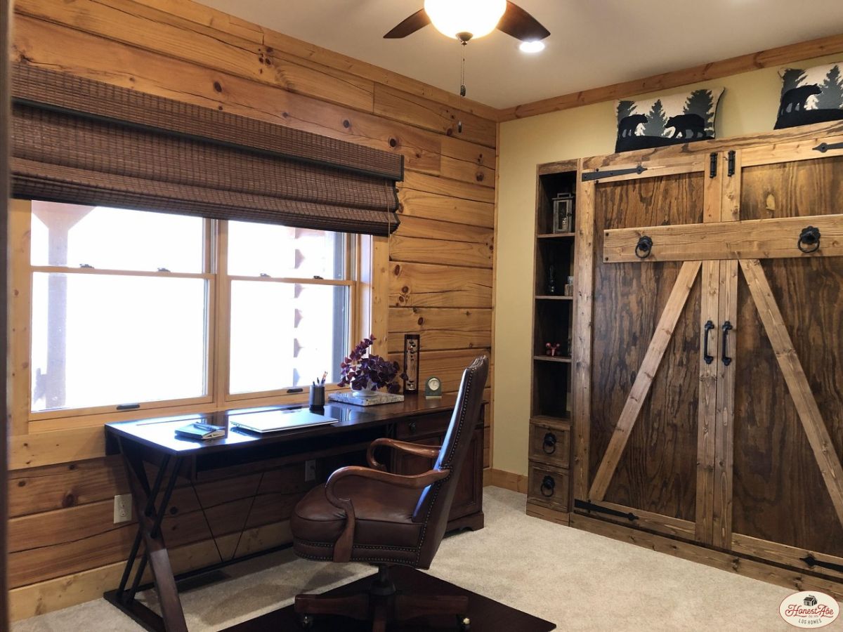 dark wood desk under window with murphy bed on right of room