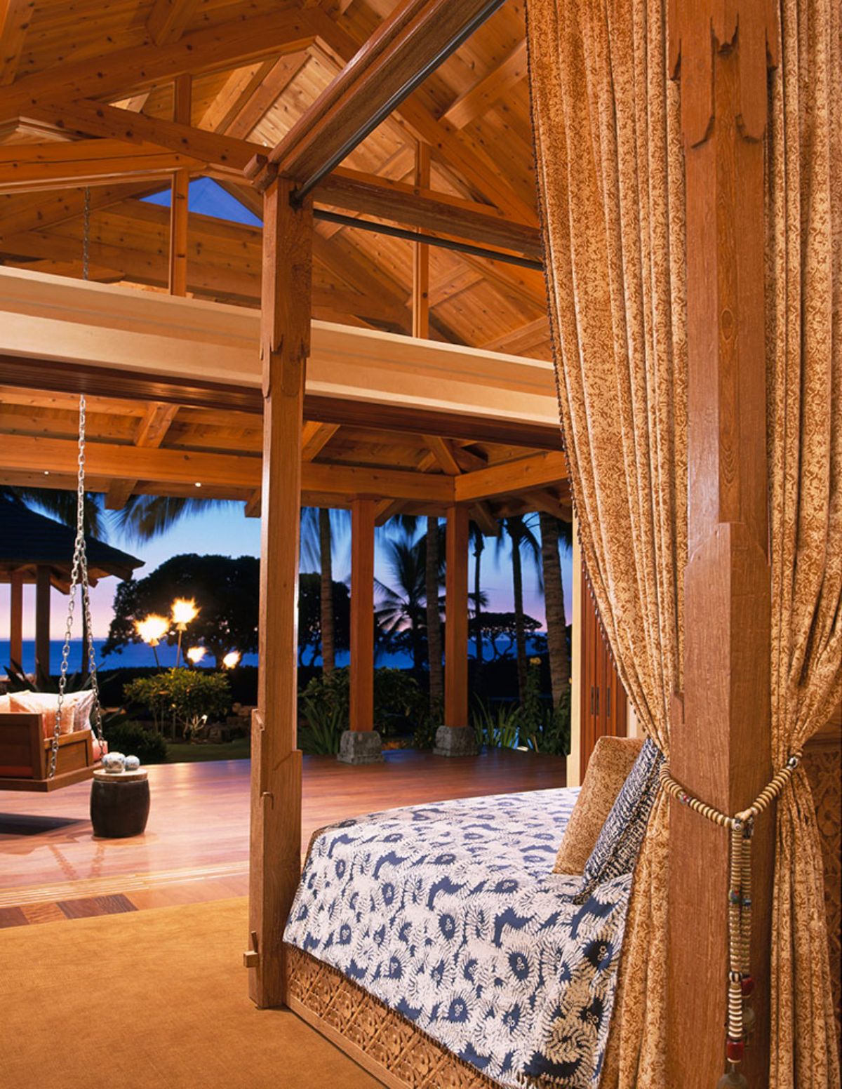 view out open side of log cabin with bed in foreground