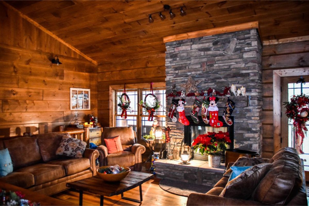 stone fireplace on far right wall with stockings hung and christmas decor on widnows
