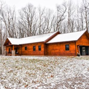 log log cabin with two car garage on end and snow covered yard
