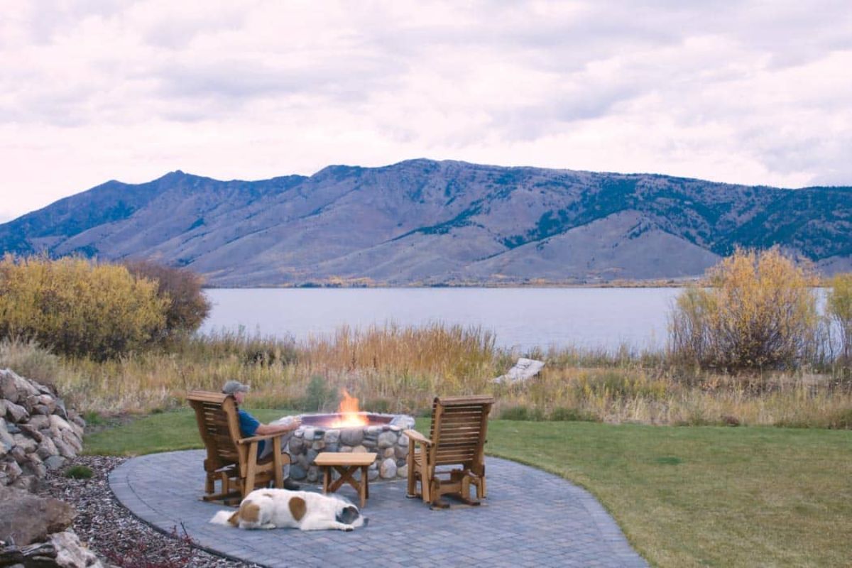 deck with wicker chairs overlooking water with hill in background