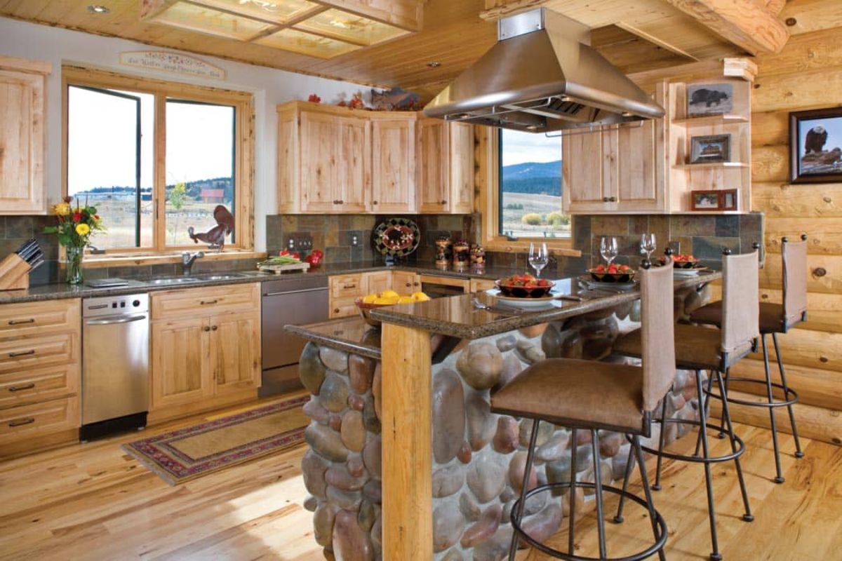 view into kitchen with stone surround on bar and large stainless steel vent hood above stove