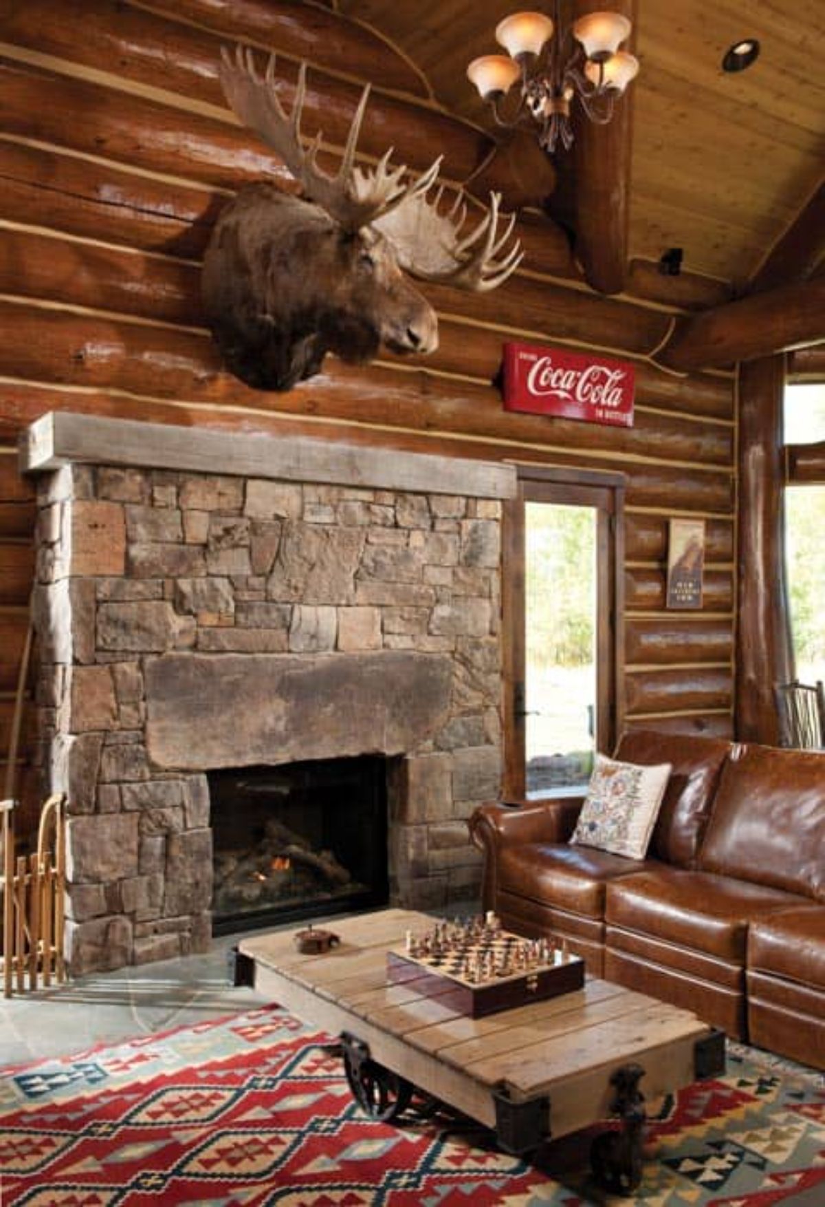 brown leather sofa in front of stone fireplace with moose head