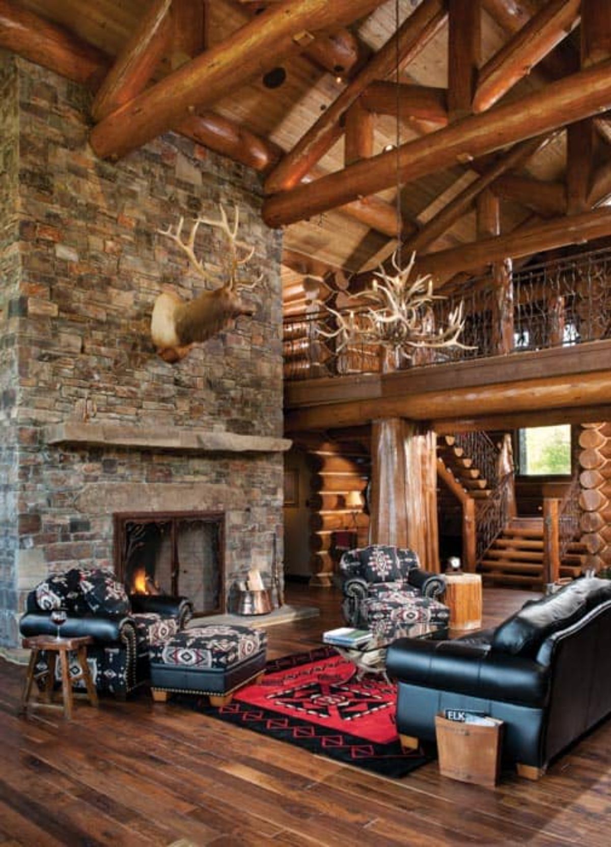stone fireplace in living rea with loft in background and black leather sofa in foreground