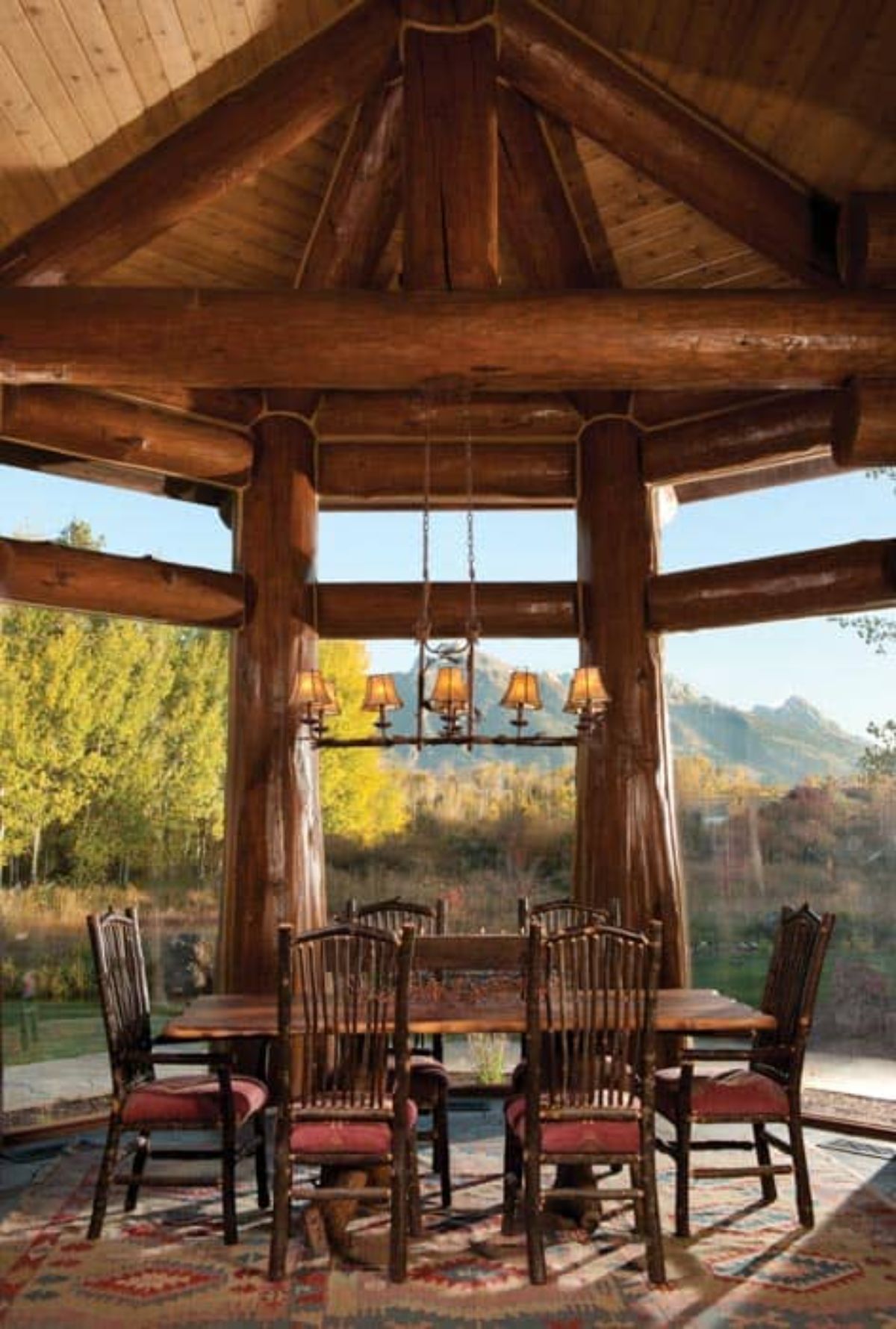 wood dining table under open beam ceiling in sunroom