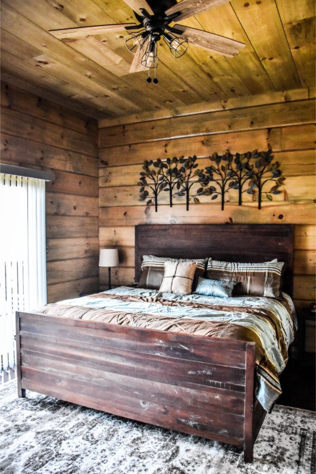 wood bed frame on bed in wood lined cabin bedroom