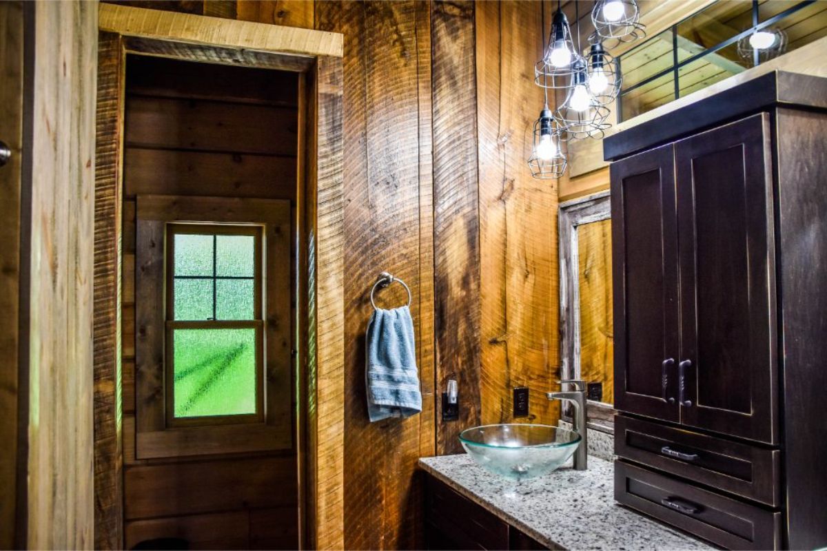 open door on left to bathroom with dark cabinet vanity on right