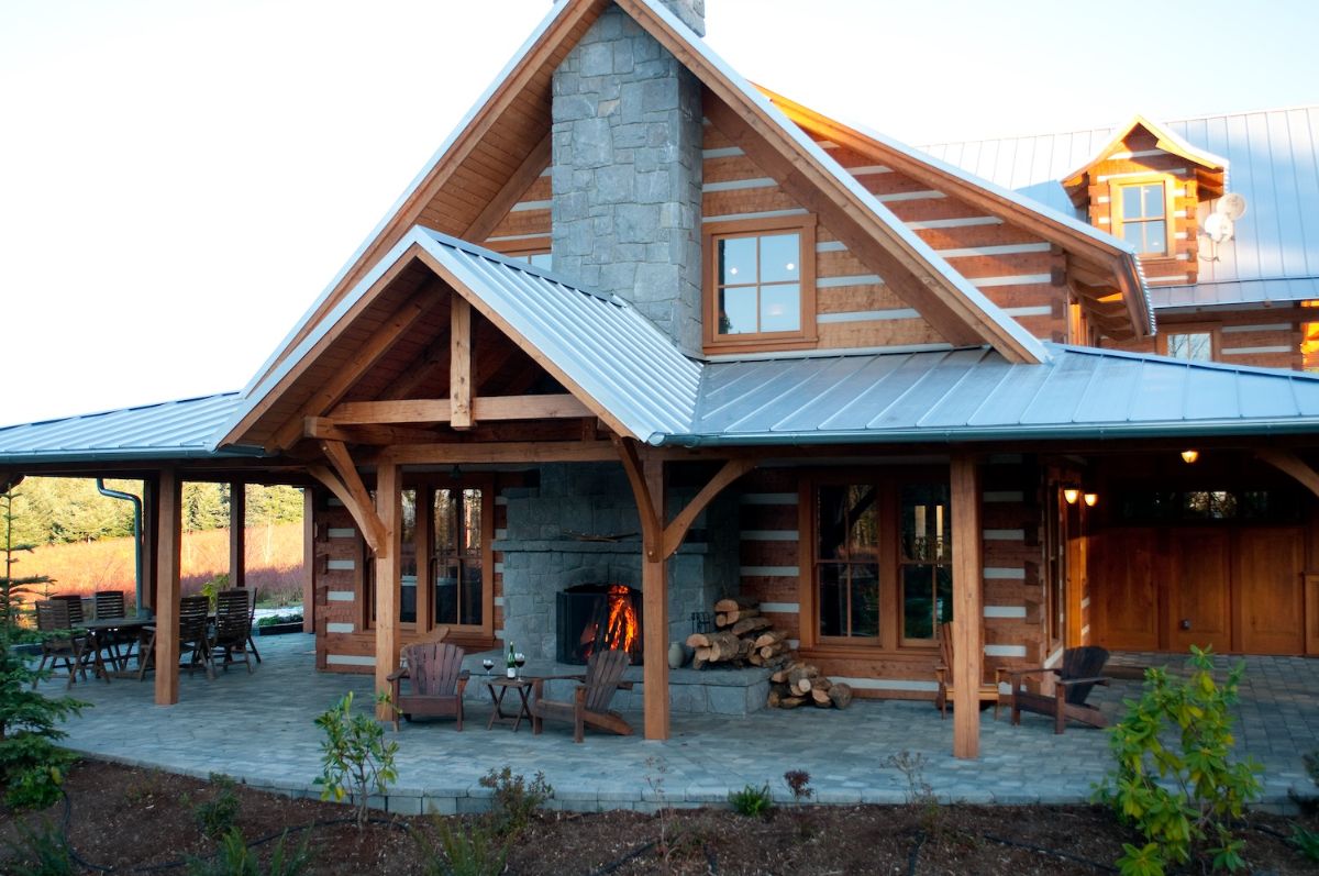 side of log cabin with chimney and outside fireplace under awning