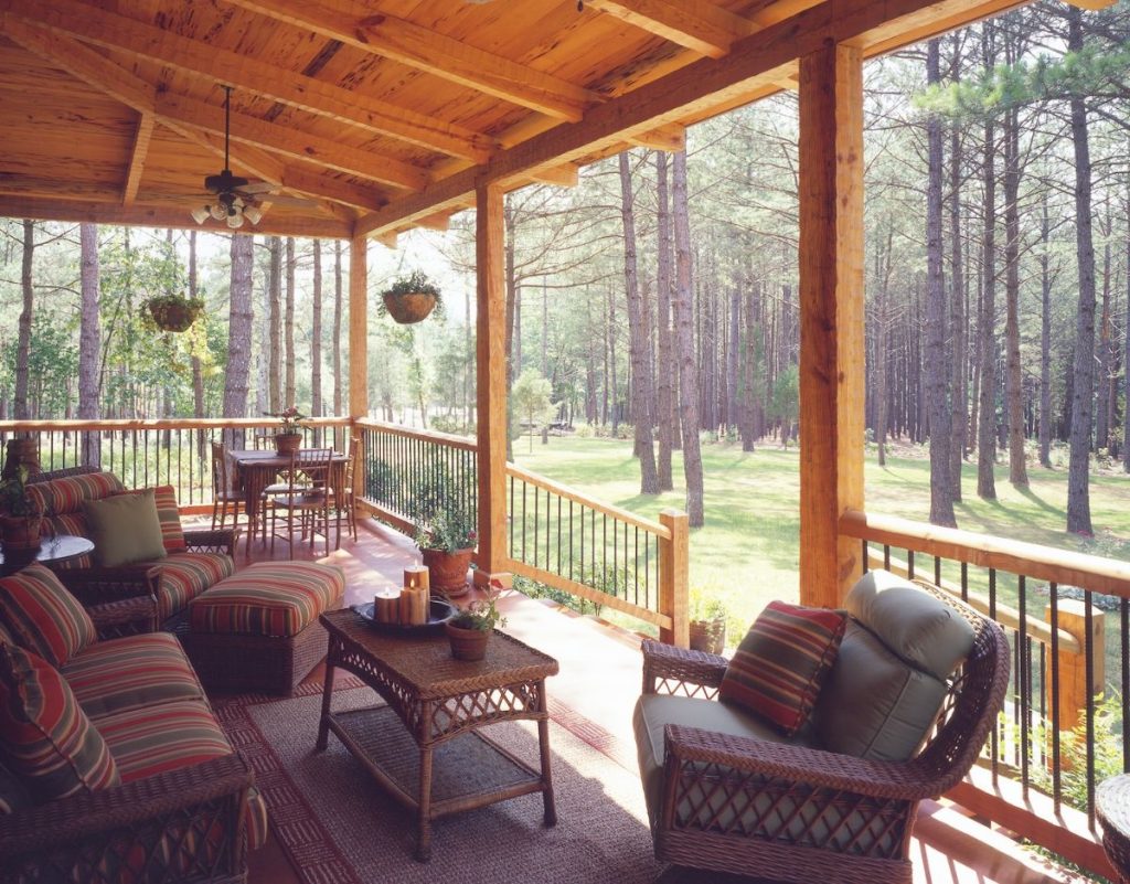 wicker furniture on covered porch of log cabin