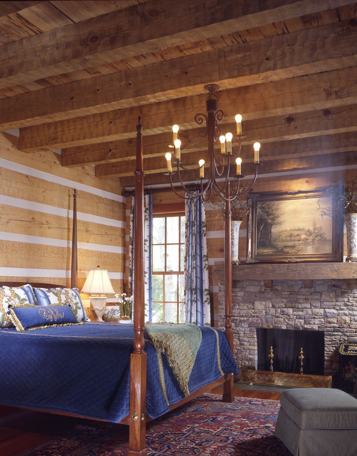 blue linens on four poster bed with fireplace against back wall