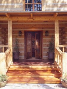 open front door on porch of log cabin