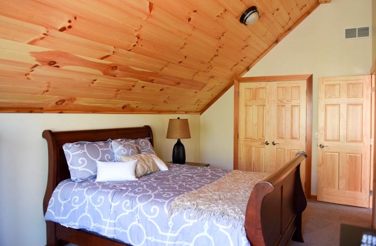 whiet linens on bed with dark wood frame in loft bedroom