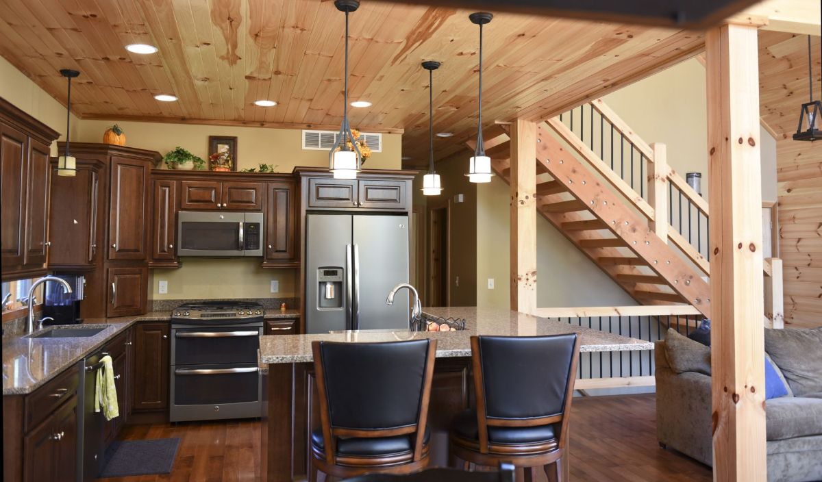 black high back stools in foreground of kitchen with stainless steel refrigerator in background