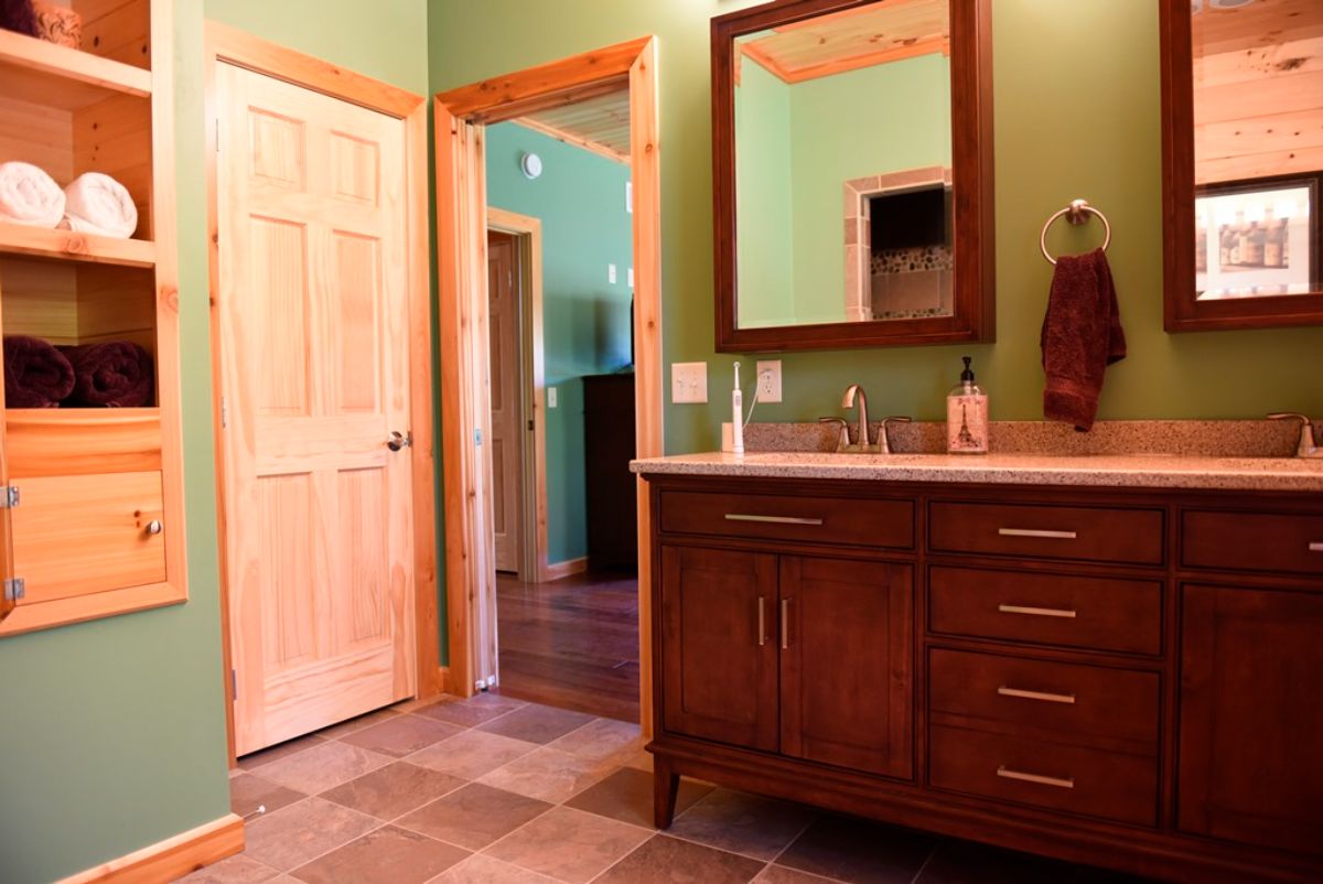 green walls above dark wood cabinet and mirror in log cabin