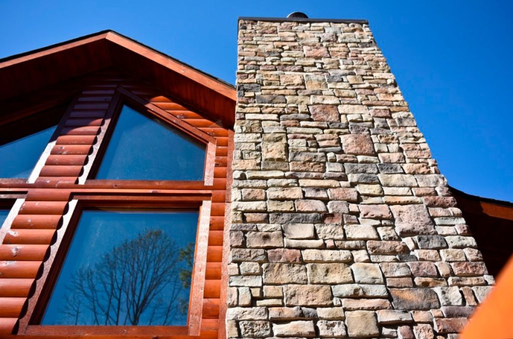 close up image of stone chimney on log cabin