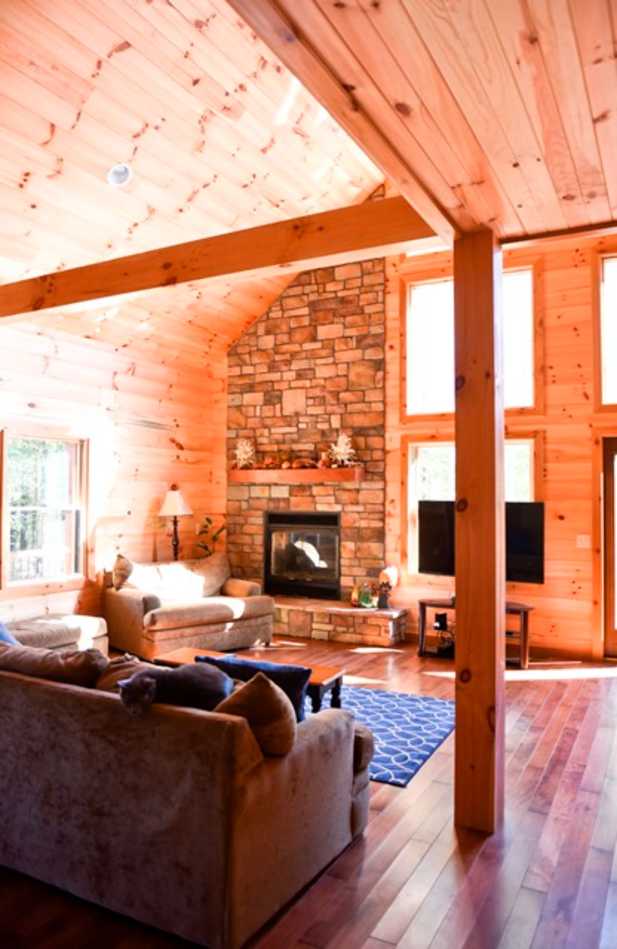 open living room in log cabin with stone fireplace on far left of image