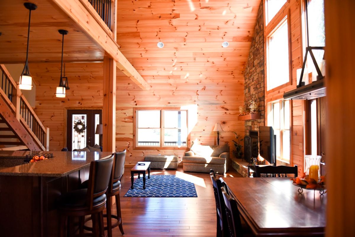 view across dining table into log cabin living room with windows on left of image