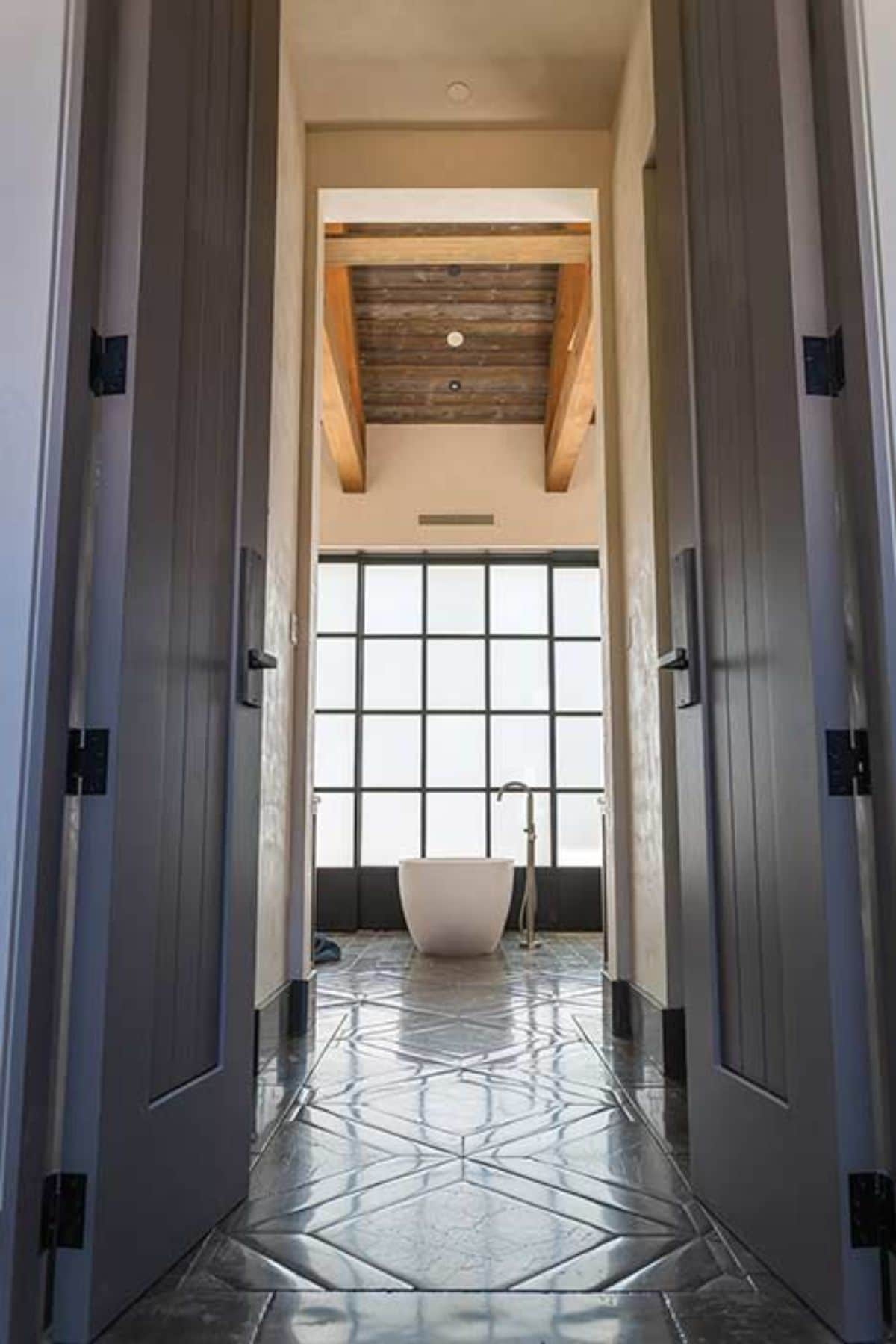 view through bathroom door to soaking bathtub in front of frosted glass windows