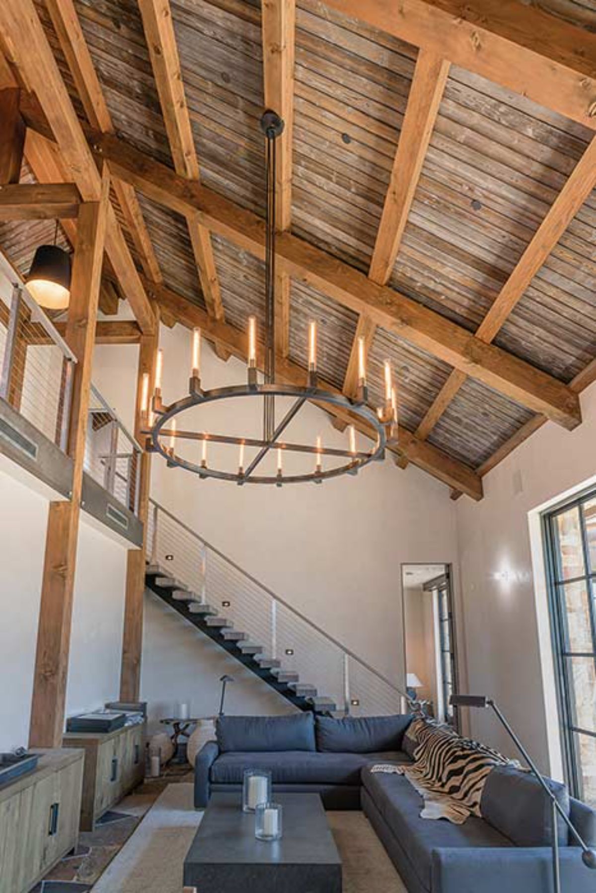 wagon wheel styled chandelier above sofas with stairs in background