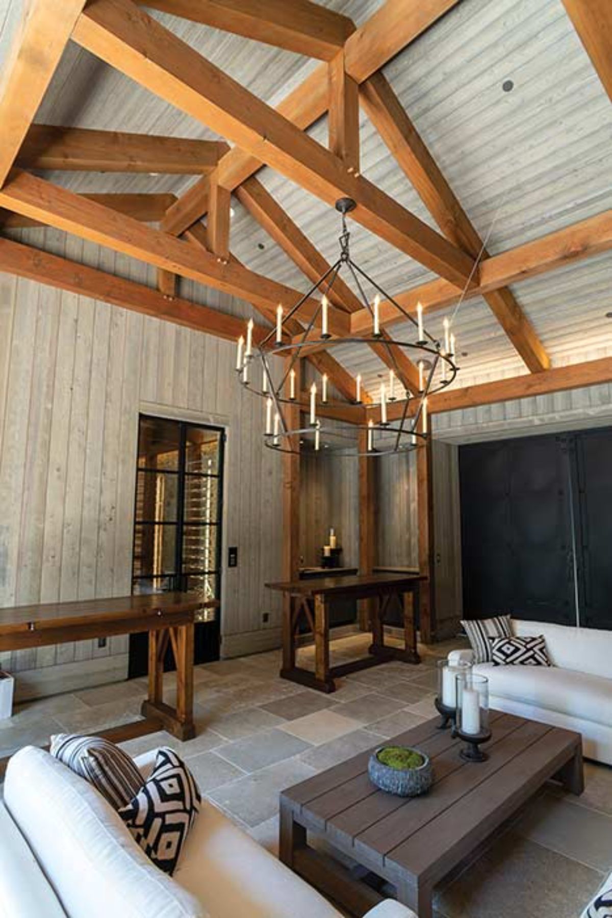 wood benches along walls with wagon wheel candle chandelier above table and chairs in middle of room