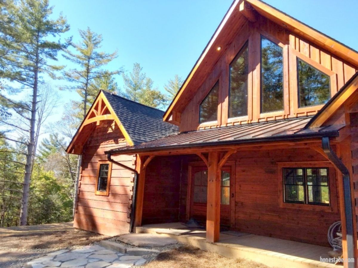 front of log cabin with windows above porch covering