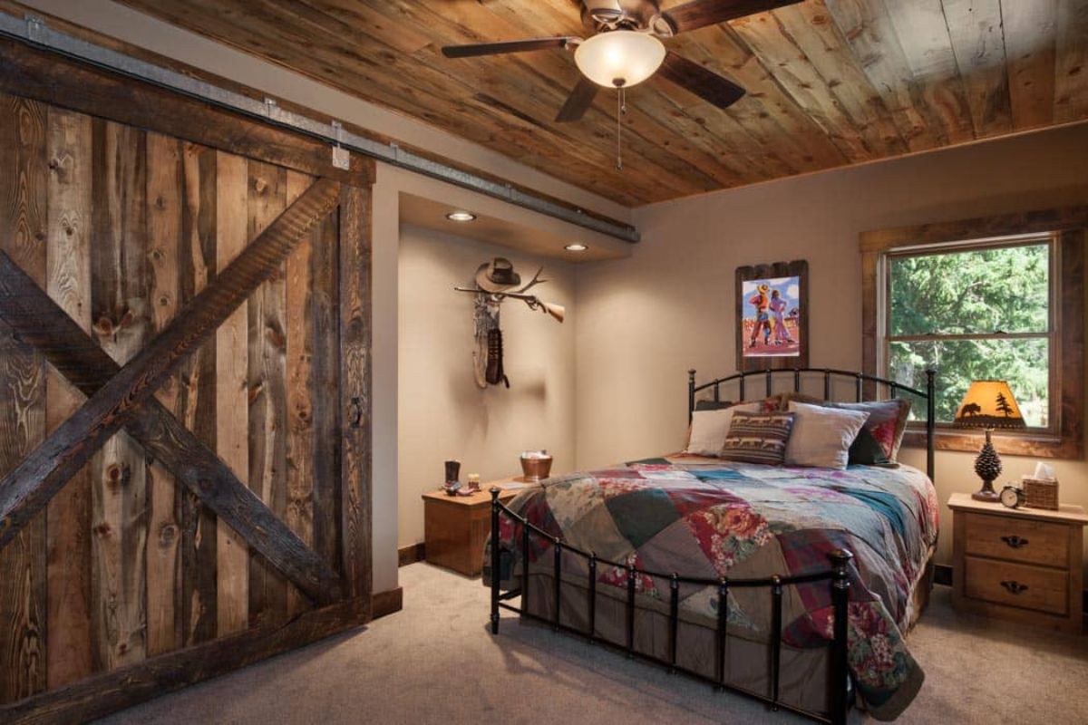 iron bed frame with quilt and barn door closure in bedroom