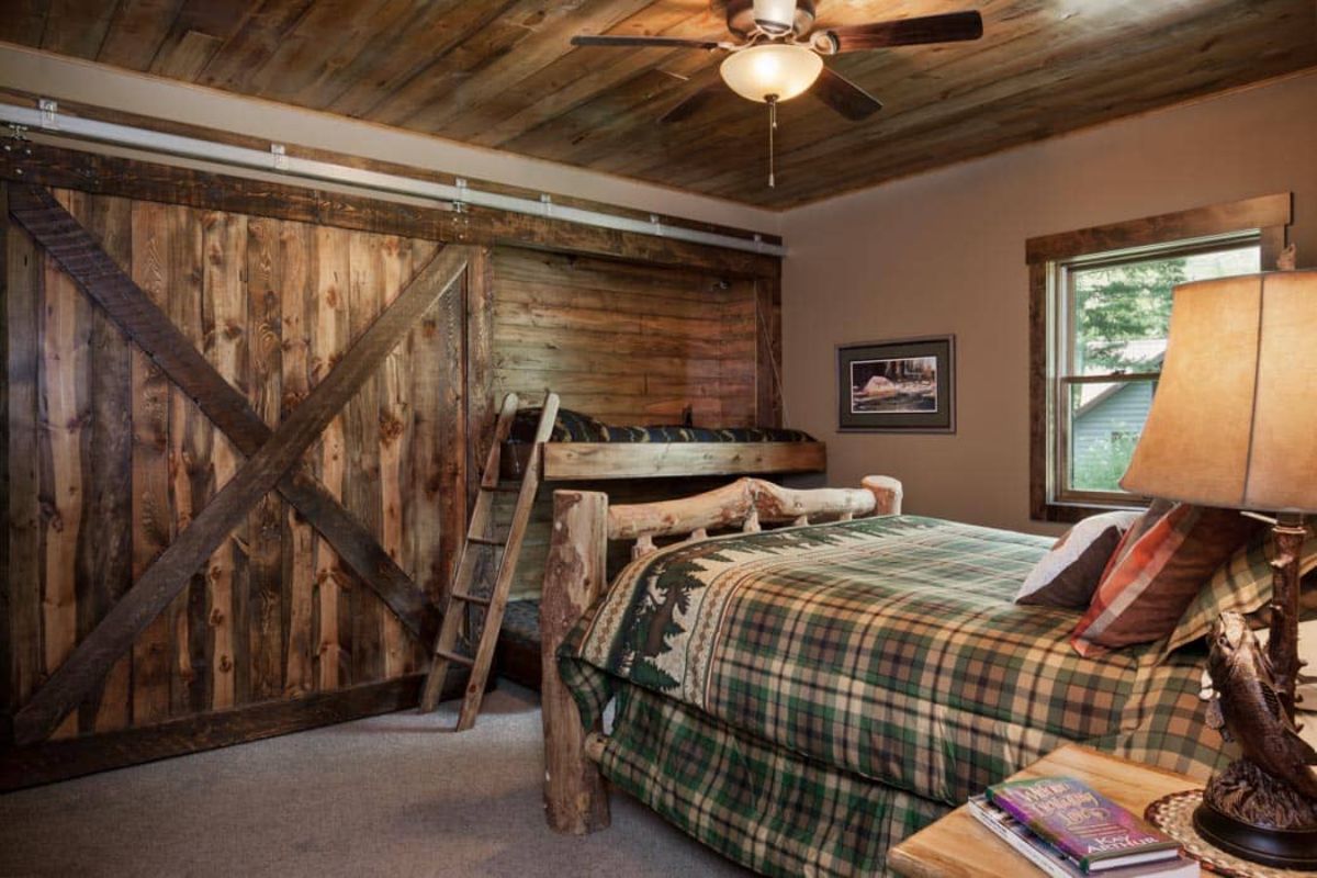 flannel bedding on wood bed frame with reclaimed wood barn door closure on room