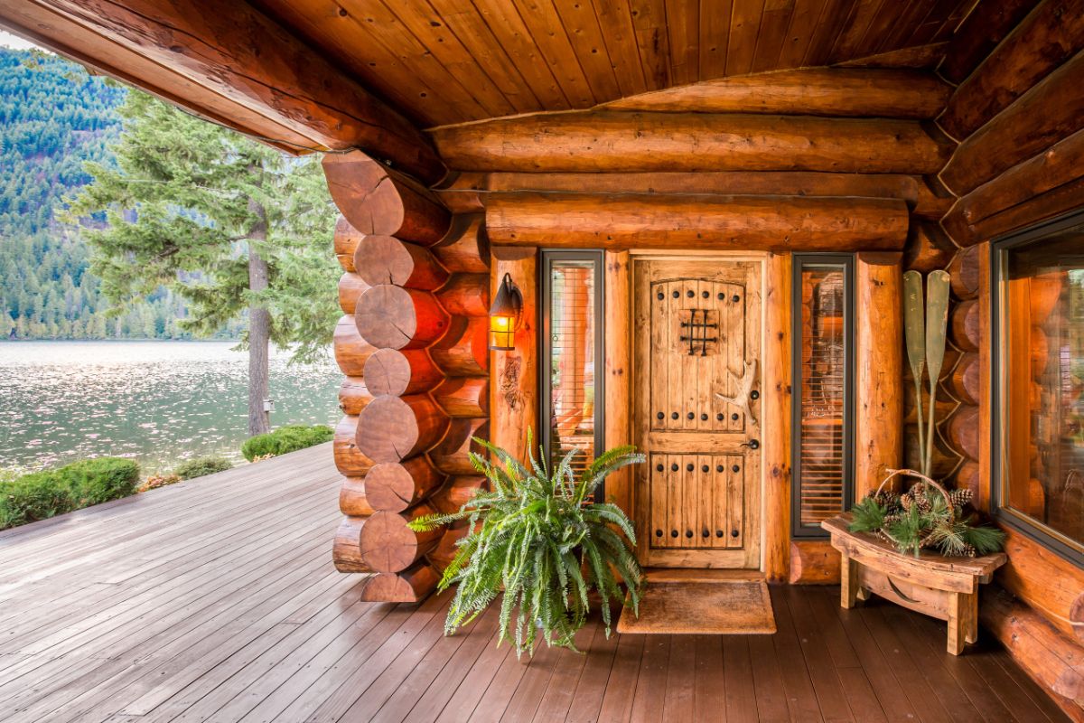 covered porch with log door and fern beside door