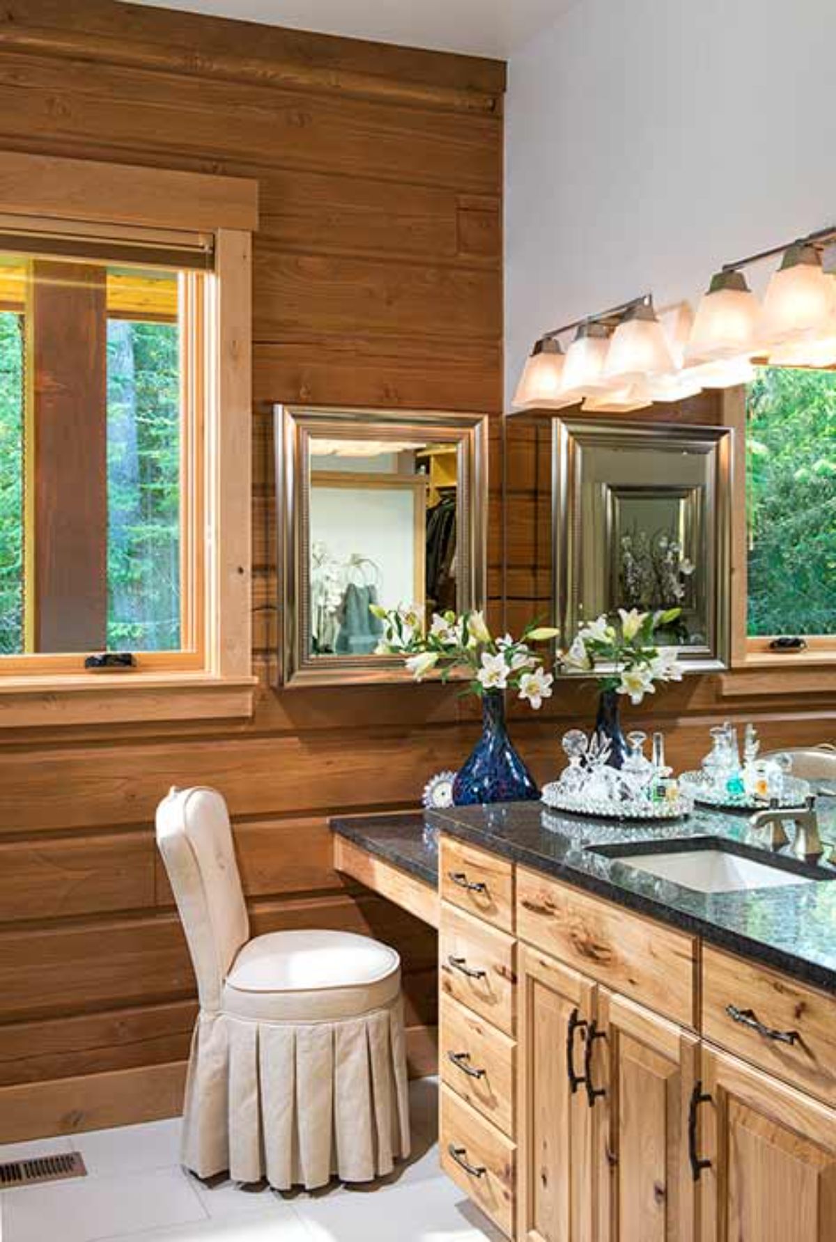 white chair under vanity of bathroom with dark countertops