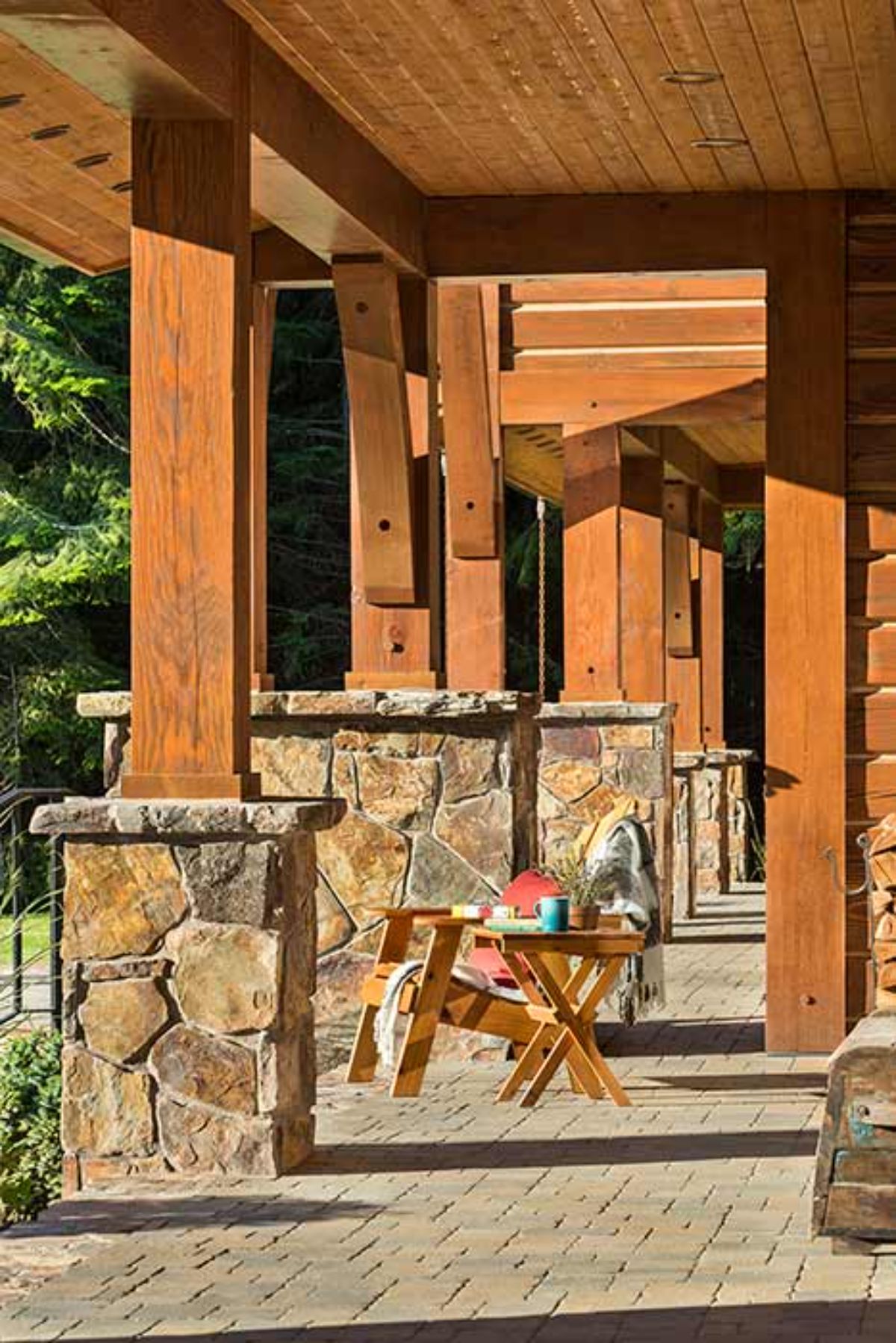 view across covered porch on log cabin with stone base on columns