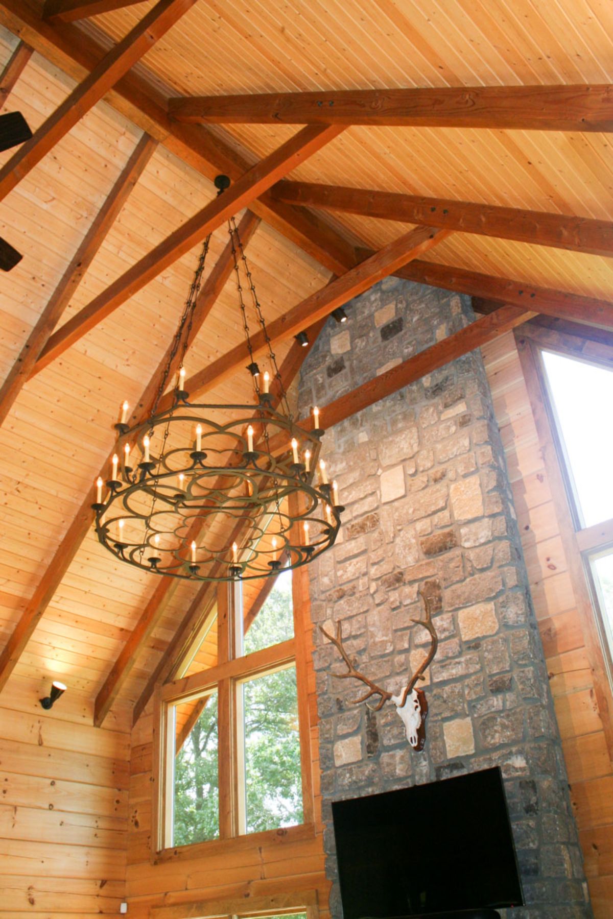 antler chandelier hanging above great room with stone fireplace in background