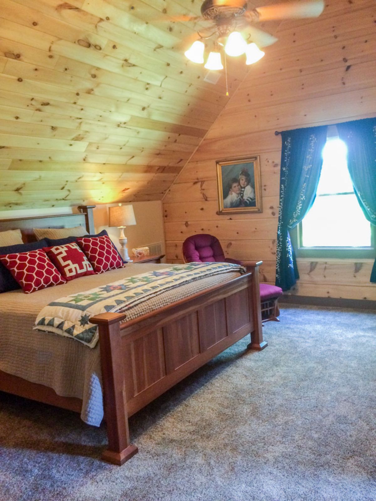 wood bedframe on bed with red and black pillow in log cabin loft