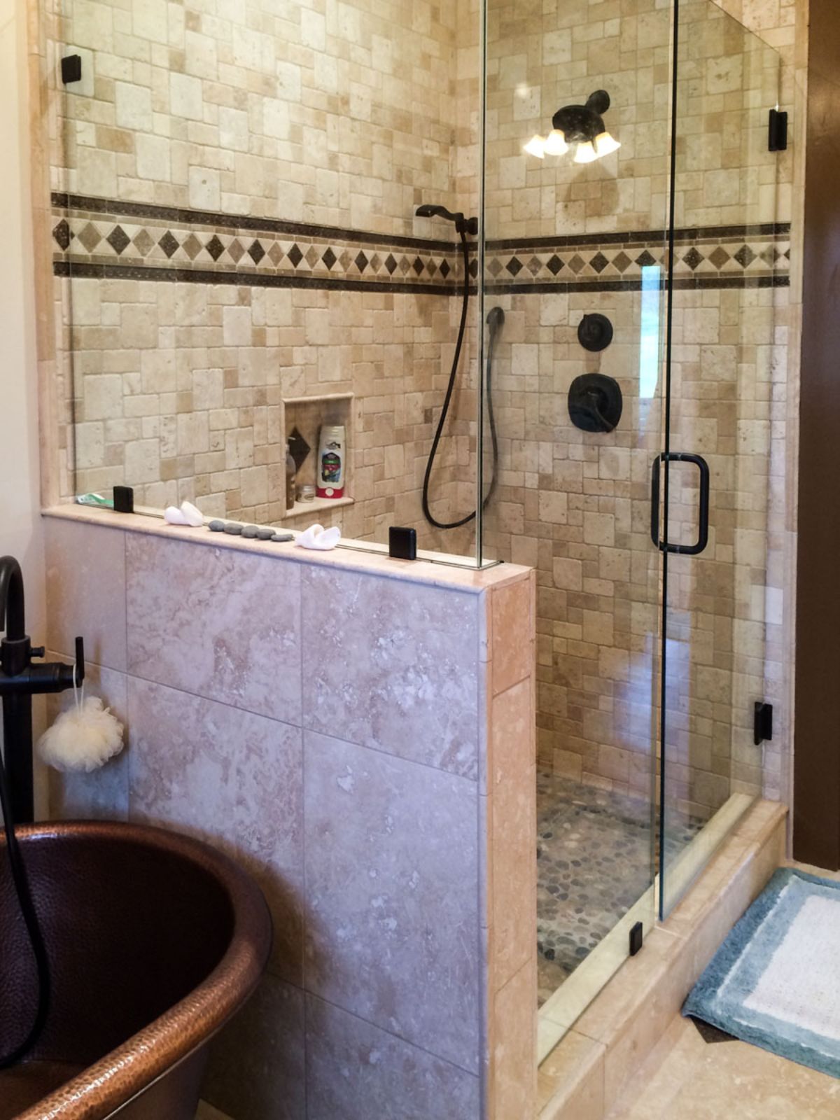 cream and brown tiled shower with halfwall and glass soor