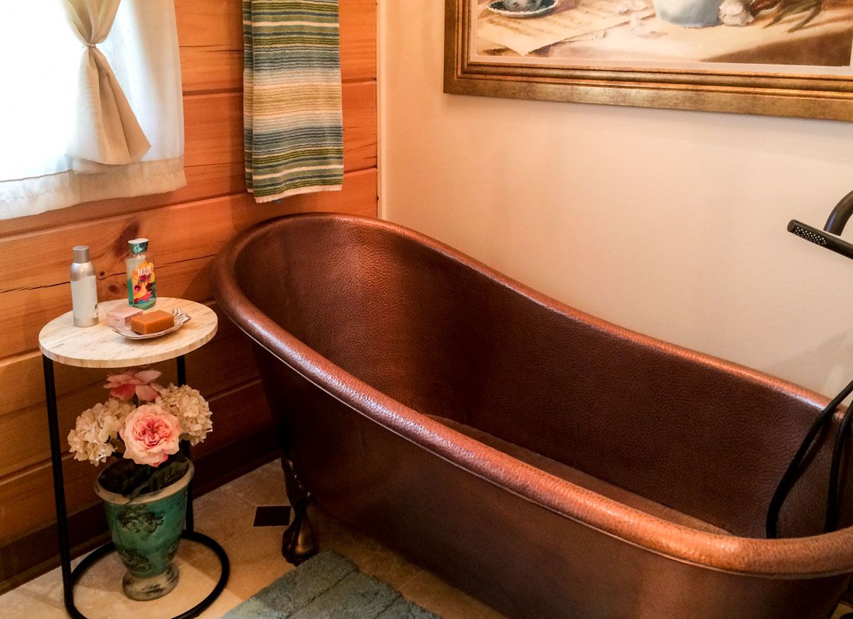 copper soaking bathtub against wall of bathroom