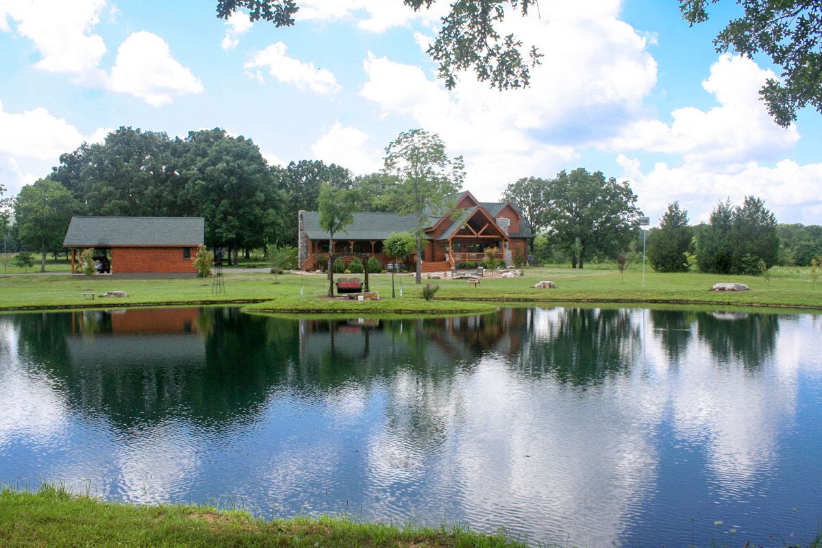 log cabin across pond with green roof