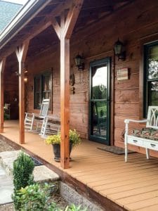 front porch of log cabin with white bench by door