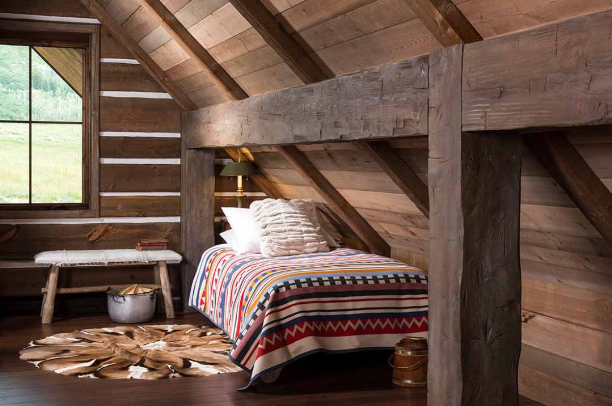 bed with striped bedding in corner of loft cabin bedframe
