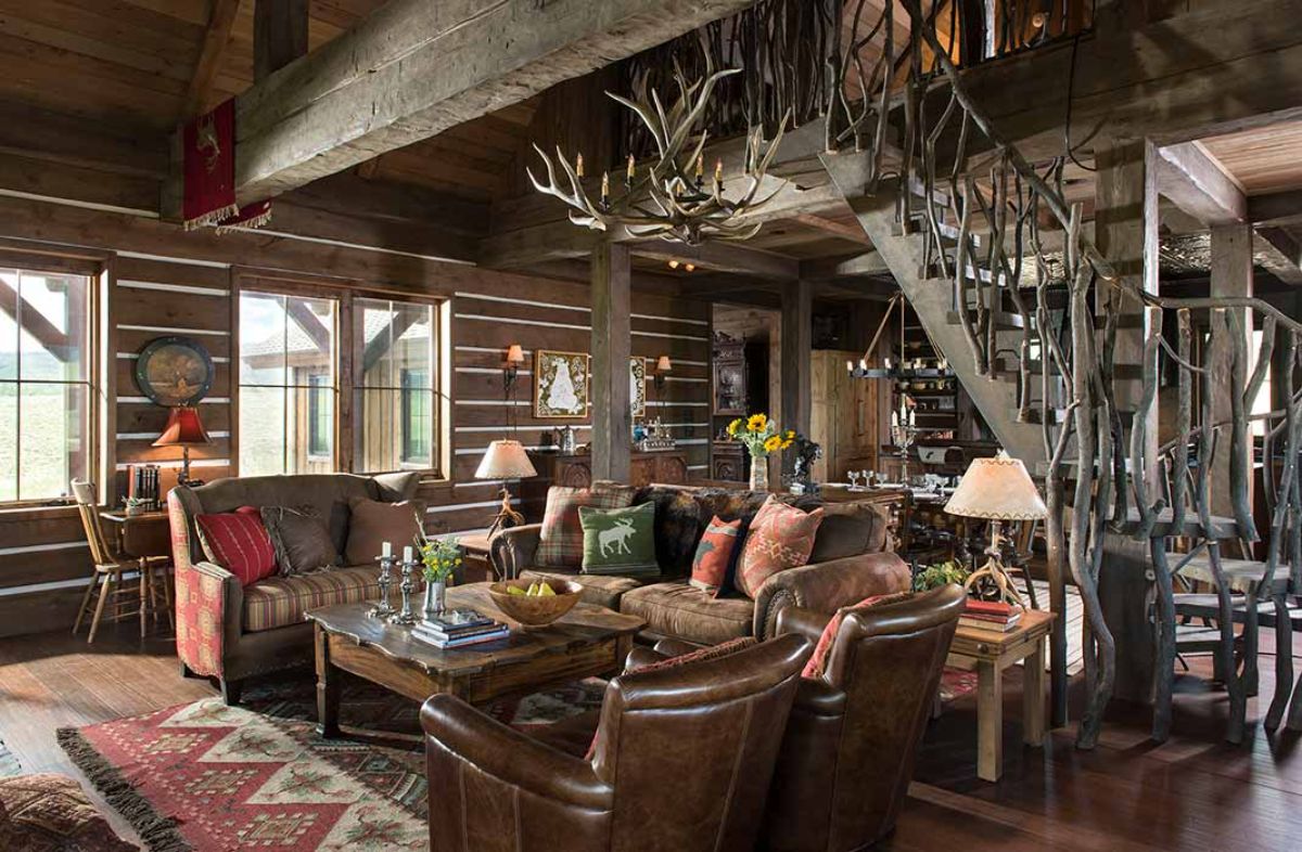 brown leather chairs in living area with rustic staircase in right background