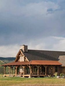 log cabin in field with covered porch with red roof