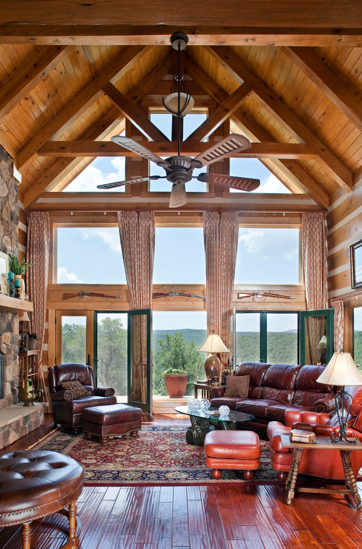 wall of windows looking out over mountains behind brown leather sofas