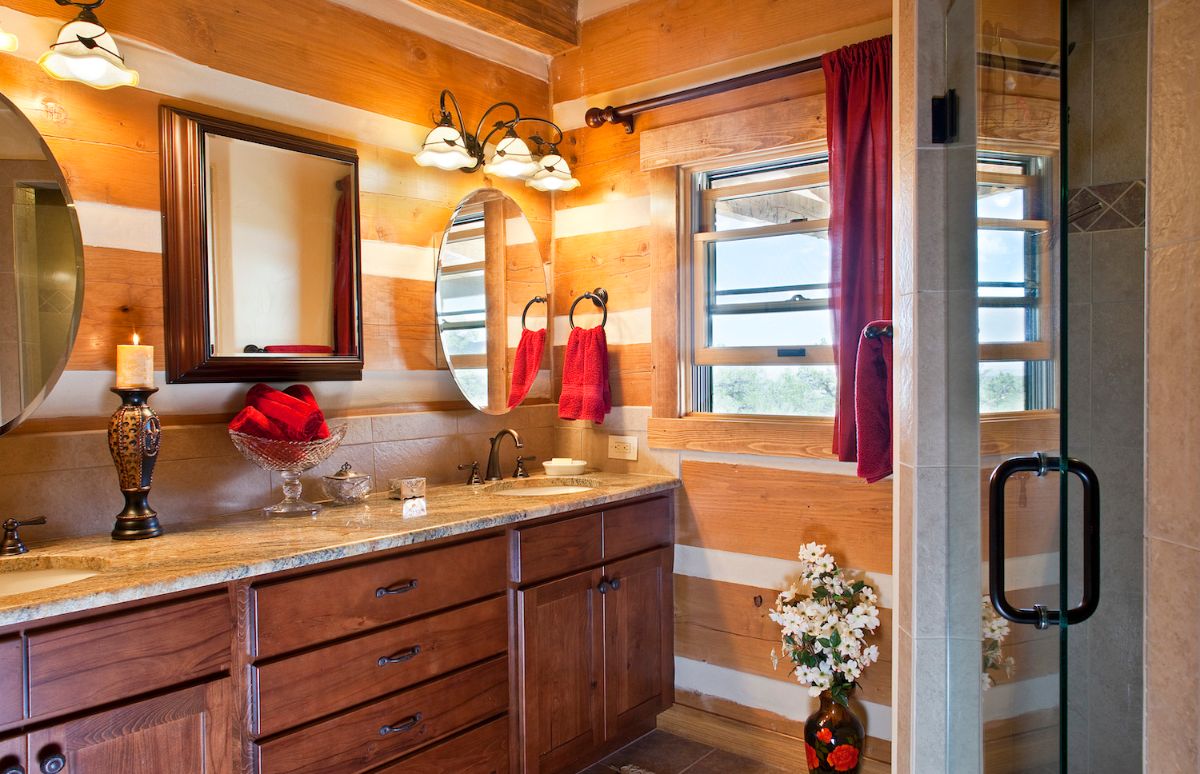 chinked wood walls in bathroom with dual vanity and shower door in foreground